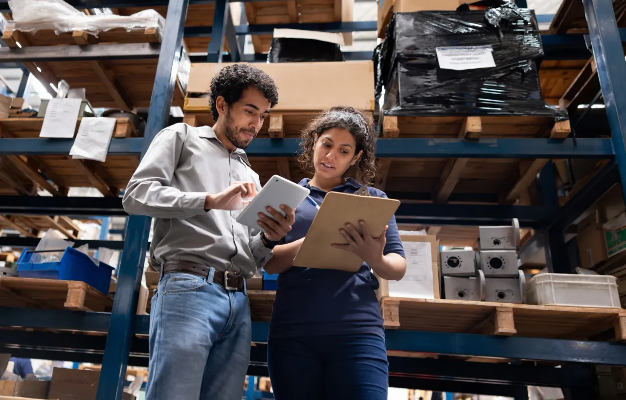 Two warehouse workers reviewing inventory with tablet