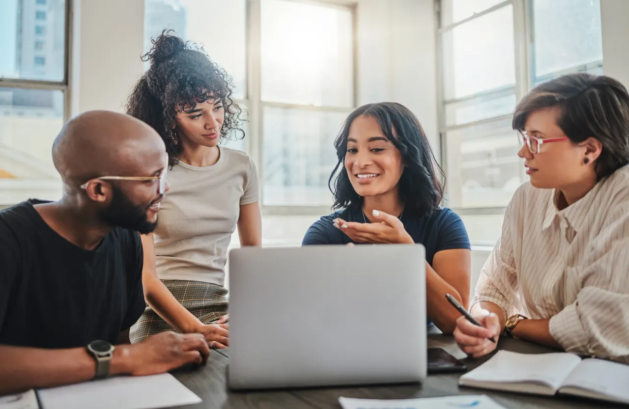 Diverse team collaborating around laptop